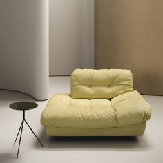 a yellow chair sitting next to a table in a room with white walls and flooring