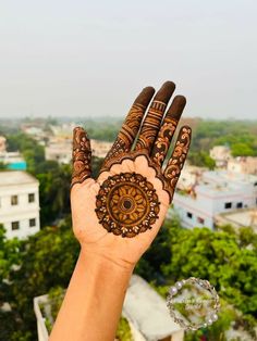 a person's hand with henna on it and trees in the back ground