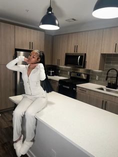 a woman sitting on top of a counter in a kitchen