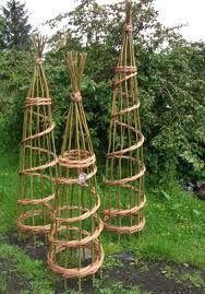 three small wooden trees made out of bamboo sticks and wire, sitting in the grass