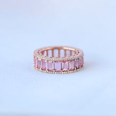 an image of a pink ring with diamonds on it's sides and in the middle