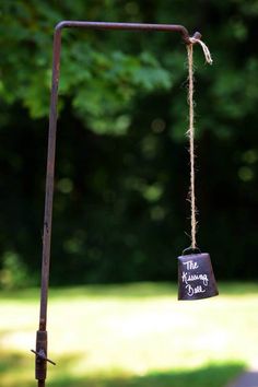 a metal pole with a sign hanging from it's side in front of some trees