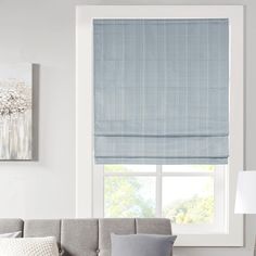 a living room with a gray couch and blue roman shades on the window sill