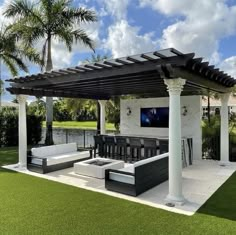 an outdoor living area with couches, tables and a television on the back wall