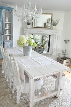 a dining room table with white chairs and flowers