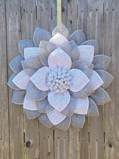 a blue and white mesh flower hanging on a wooden fence