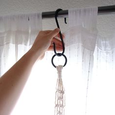 a hand is holding the curtain rod with an object hanging from it's end