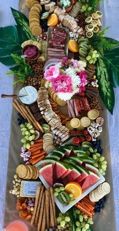 an assortment of food is laid out on a table with flowers and leaves around it