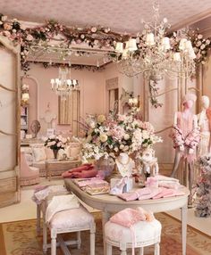 a room filled with lots of furniture and flowers on the table in front of a chandelier