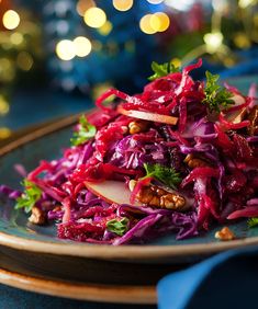 red cabbage salad with walnuts and parsley on a blue plate in front of christmas lights