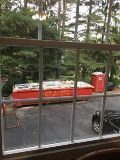 a red train car sitting on the side of a road next to a parking lot