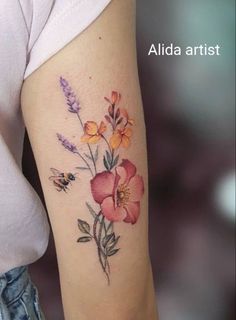 a woman's arm with flowers on it and a bee in the middle of her arm