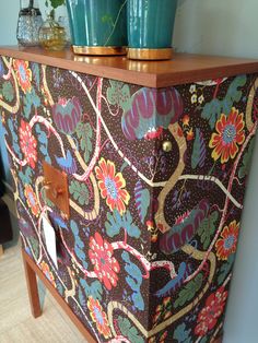 two green vases sitting on top of a colorful dresser