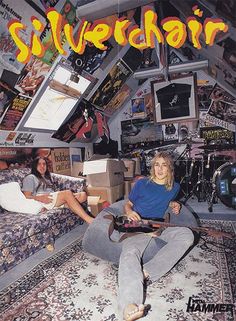 two women sitting on a couch in a room filled with guitars and other musical equipment