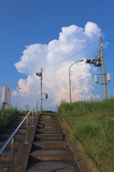 the sky is very cloudy and there are some stairs going up to it with traffic lights on each side