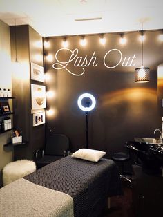 a salon room with lights on the wall and a black bed in front of it