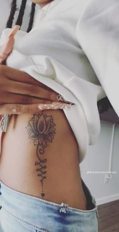 a woman's stomach with tattoos on it and her hand resting on the belly