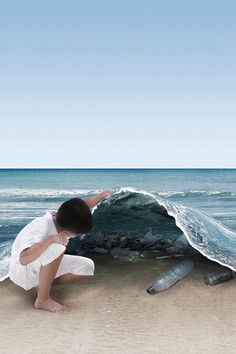 a young boy kneeling on the beach next to an ocean wave and two dead fish