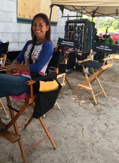 a woman sitting in a chair under an umbrella