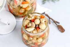 two jars filled with food sitting on top of a table next to utensils