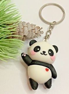 a panda bear keychain sitting next to a pine cone