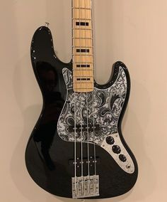 an electric bass guitar hanging on the wall with a black and white floral print body