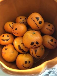 oranges with faces drawn on them in a bowl