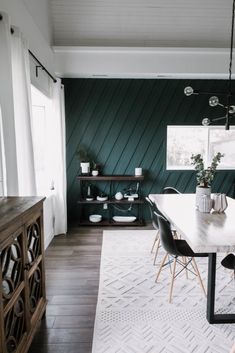 a dining room with dark green walls and white rug