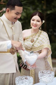 a man and woman standing next to each other in front of a table filled with dishes