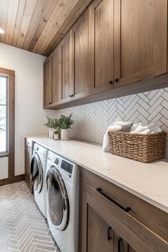 a washer and dryer sitting in a room next to a window with wooden cabinets