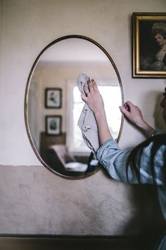 a woman is looking at her reflection in the mirror while she brushes her nails with a cloth