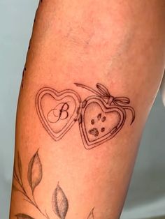 two heart shaped tattoos on the legs of a woman's leg, with leaves and flowers around them