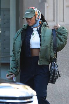 a woman walking down the street wearing a green jacket