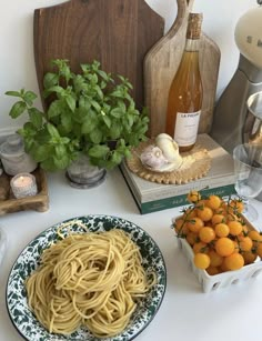 a table topped with oranges and pasta next to bottles of wine on top of a wooden cutting board