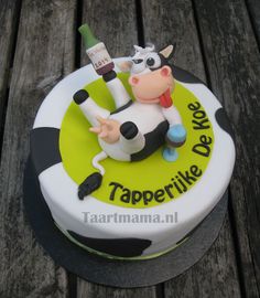 a cake with a cow on it sitting on top of a wooden table next to a bottle