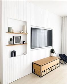 a tv mounted on the wall in a living room next to two shelves with baskets