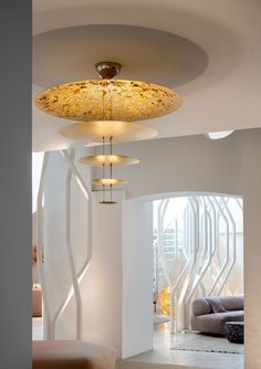 a living room filled with lots of furniture next to a white wall and ceiling light