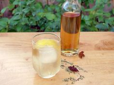 a bottle of tea next to a glass filled with liquid and spices on a wooden table