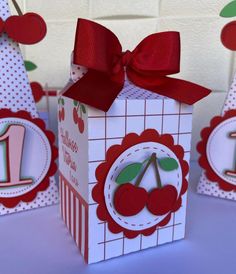 three small boxes with cherries on them and one has a red ribbon around the top