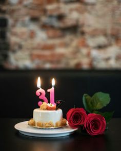 a birthday cake with three candles and two roses