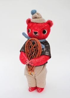 a teddy bear holding a tennis racquet in its hands and wearing a hat