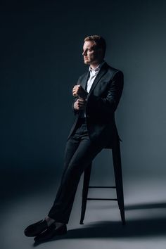 a man in a suit sitting on a stool