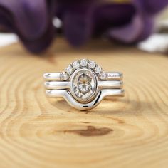 a close up of a ring on a wooden surface with flowers in the background,