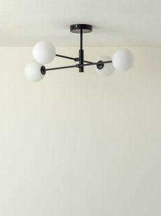 a ceiling light with five white balls hanging from it's center point in a room