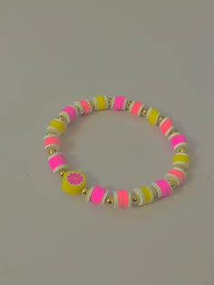 a pink, yellow and white beaded bracelet on a gray surface with gold accents