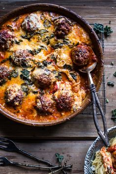 a casserole dish with meatballs and spinach in it on a wooden table