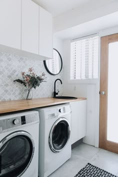 a washer and dryer in a white laundry room with wood counter tops on the floor