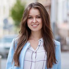 a woman standing in front of a building wearing a blue blazer and white shirt