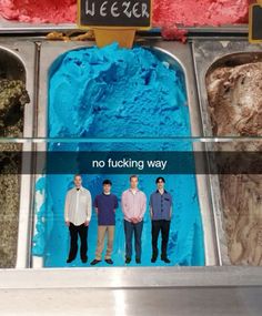 three men standing in front of an ice cream machine with blue frosting on it