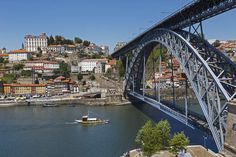 a large bridge spanning over a river with boats on it and buildings in the background